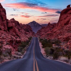 A scenic road cutting through rugged red rock canyons at sunset, symbolizing the journey rural healthcare organizations take to achieve financial stability, sustainable growth, and stronger patient care outcomes.