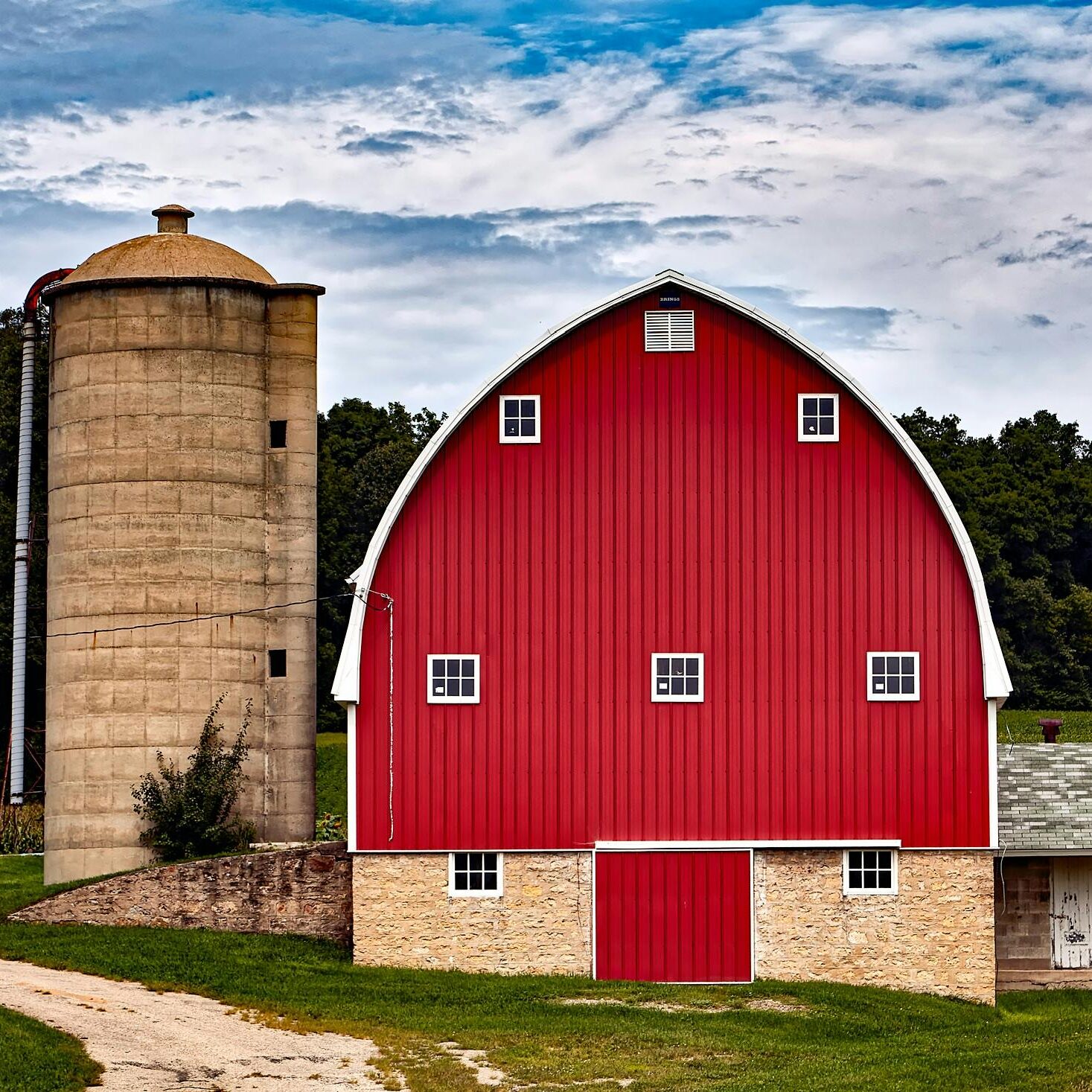 Traditional red barn and silo in an agricultural setting.