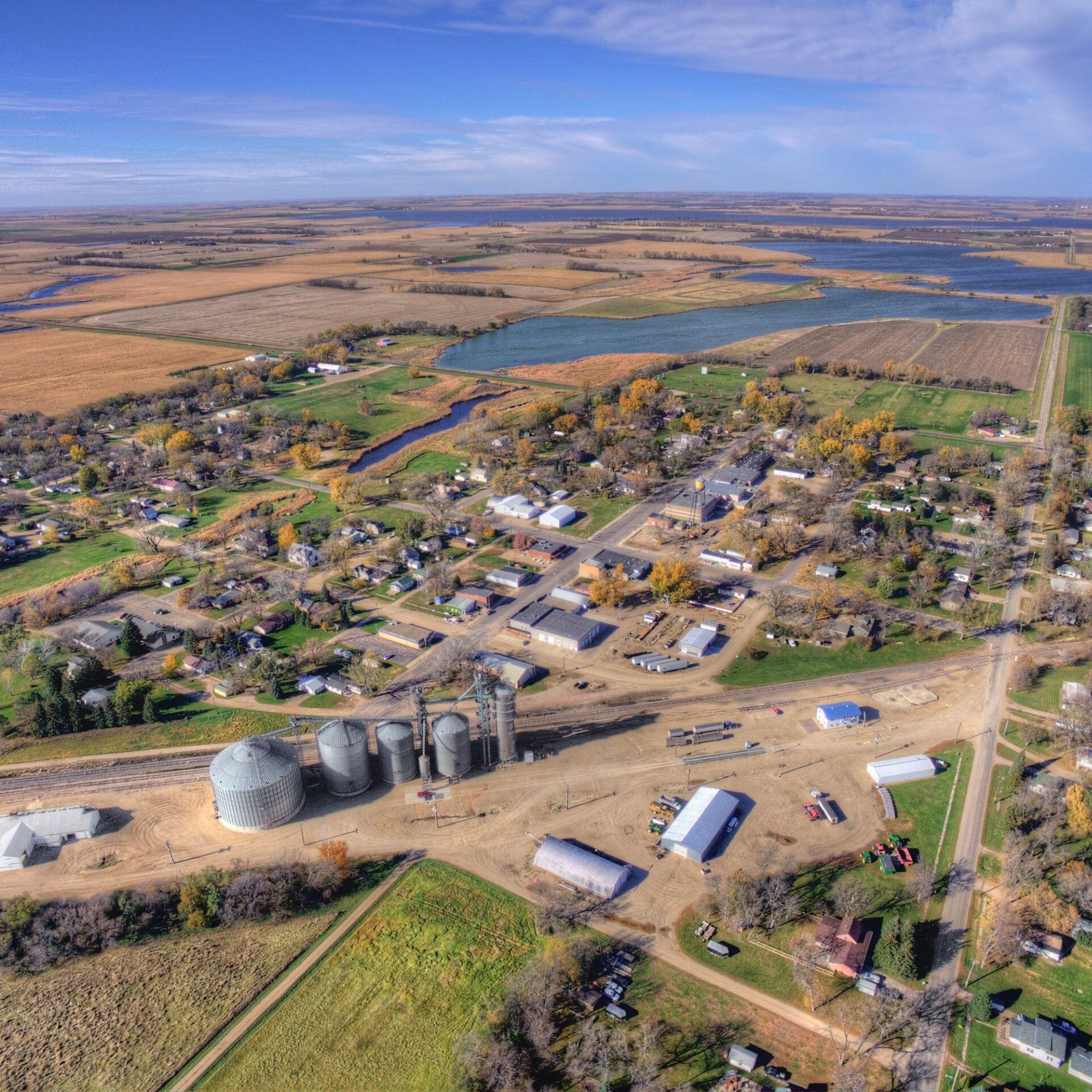 Aerial view of a small rural town surrounded by farmland, grain silos, and a lake, representing rural hospital communities