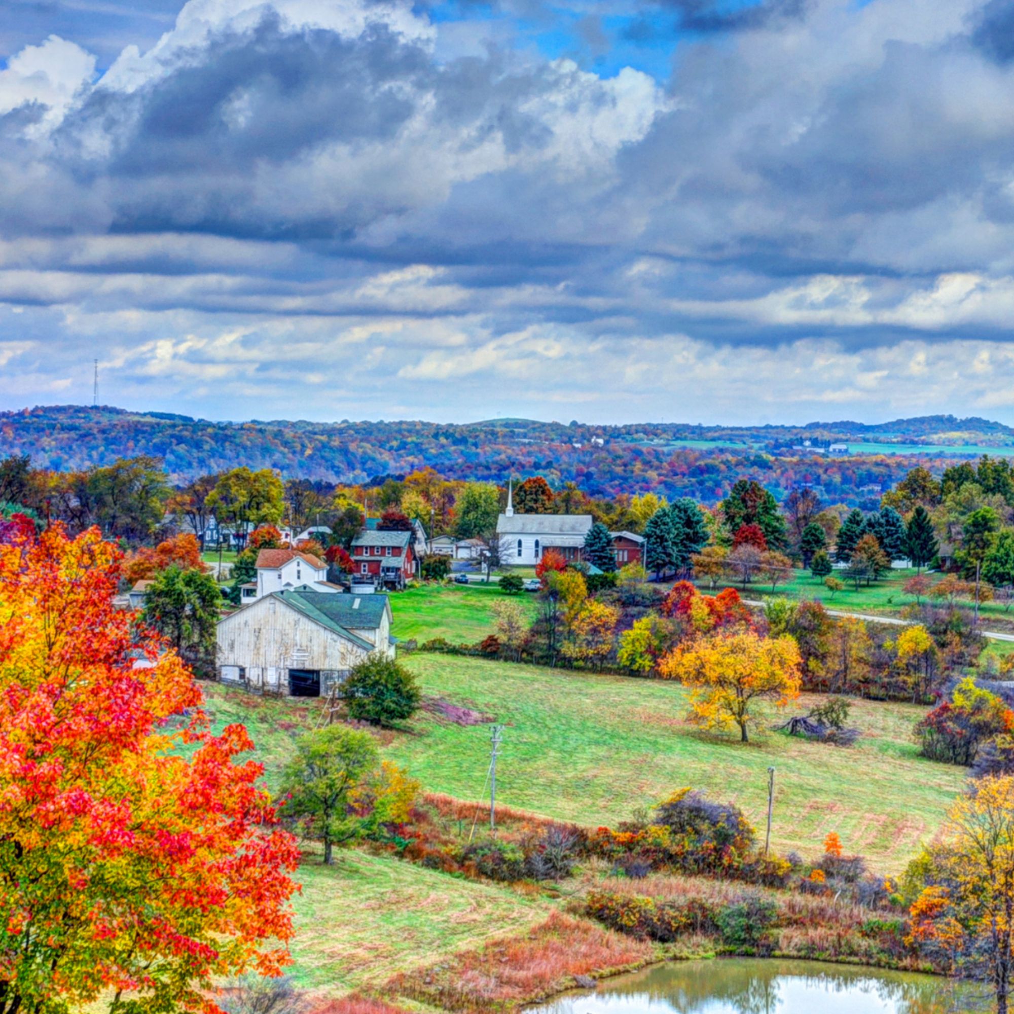 A vibrant rural landscape with fall colors and green fields.