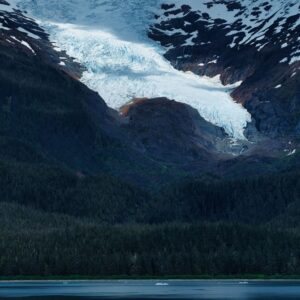 A wide landscape of Alaskan wilderness with a lake and glacier in the distance.