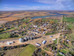 Aerial view of a small rural town surrounded by farmland, grain silos, and a lake, representing rural hospital communities