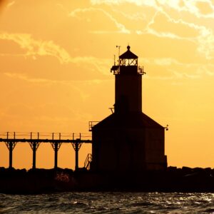 Indiana lighthouse silhouetted against a golden sunset over Lake Michigan.