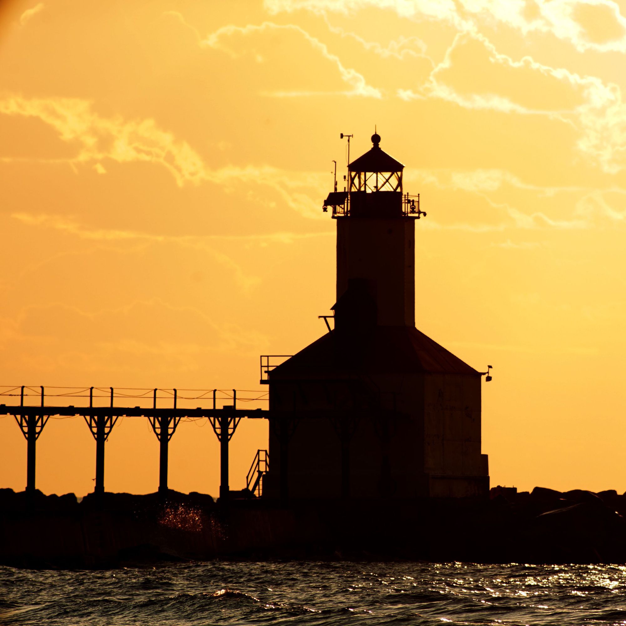 Indiana lighthouse silhouetted against a golden sunset over Lake Michigan.