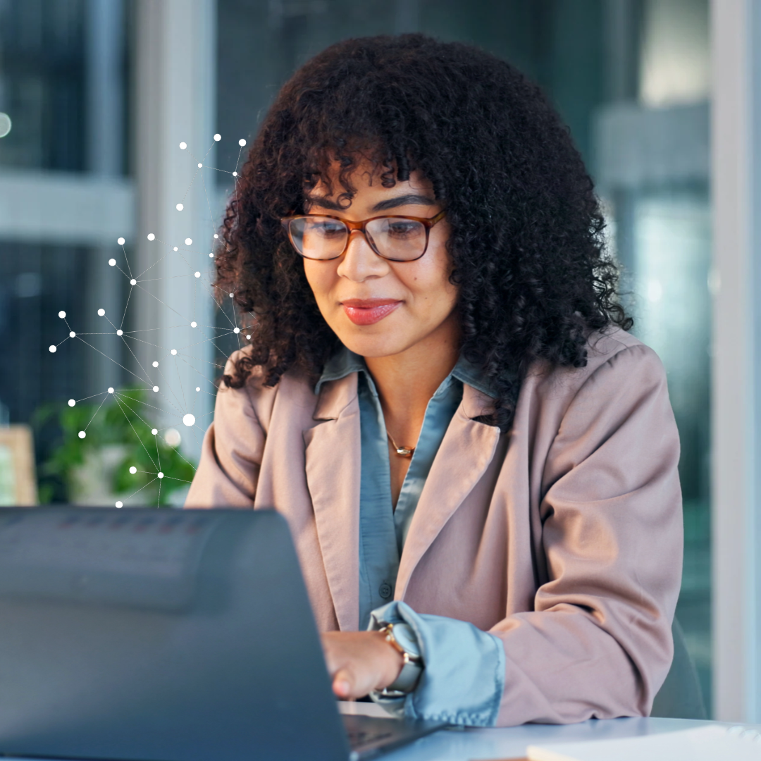 Woman wearing glasses and a blazer working on a laptop, with a digital network of connected data points representing healthcare analytics and insights.