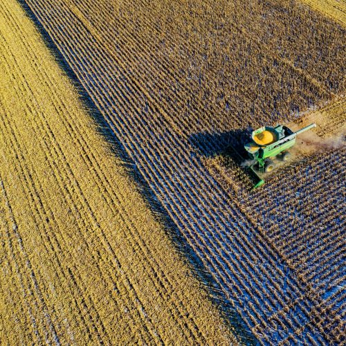 Combine harvesting a field from an aerial perspective during harvest season.